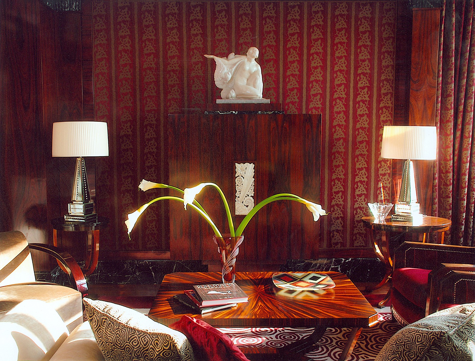Elegant interior featuring a richly patterned wall, a sculptural centerpiece, stylish lighting, and decorative accents. Ideal for design inspiration.